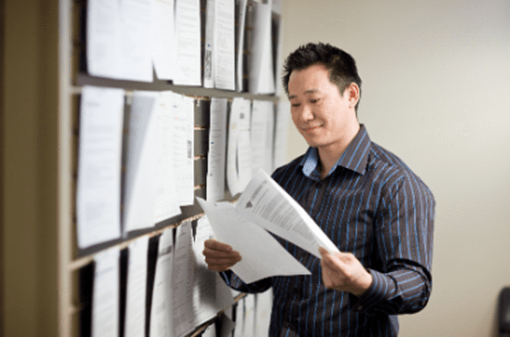 A man reading a job posting from a wall full of job postings