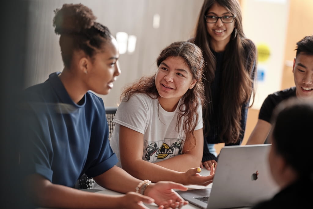 Students in conversation around a laptop