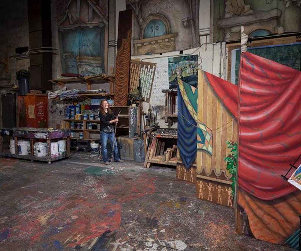 Denise Lisson standing in front of a large painted background in a studio