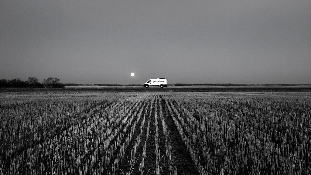 The Brandvan sitting on the road at the end of a long field.
