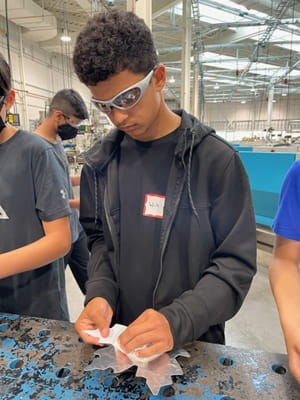 14-year-old Will Holmes-Ramroop cleans a metal maple leaf that was stamped in Sheridan's Magna Skilled Trades Centre