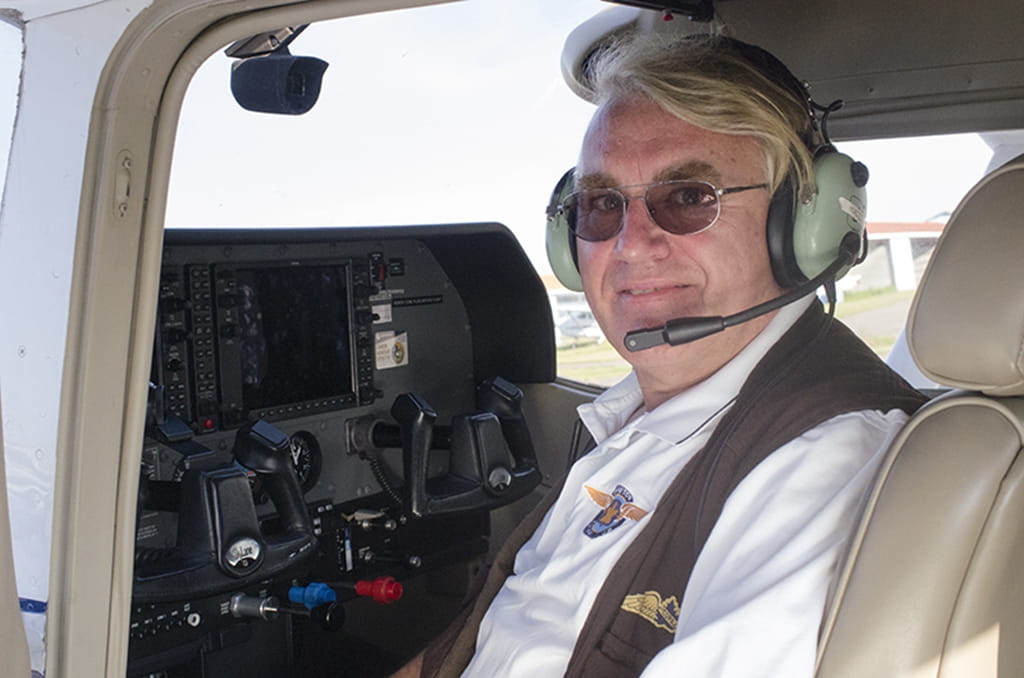 Nigel Johnson sitting in the cockpit of a small plane.